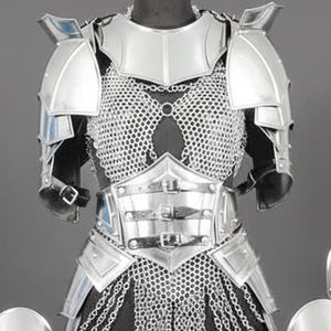 K&ouml;nnte beinhalten: Ein R&uuml;stungsset aus silberfarbenem Metall mit einem Brustpanzer aus Kettenhemd, Schulterst&uuml;cken und einem Taillenkorsett mit drei Schnallen. Das Set enth&auml;lt vier passende Beinschienen oder Armsch&uuml;tzer, die jeweils mit einem Rautenmuster gepr&auml;gt sind.