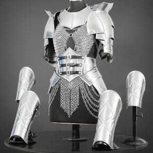 K&ouml;nnte beinhalten: Ein Set aus polierter silberner Metallr&uuml;stung mit Brustplatte, schwarzen Lederriemen, Kettenhemd-Details, Schulterst&uuml;cken und vier passenden Beinschienen. Das R&uuml;stungsset besteht aus beweglichen Metallplatten und feinen Kettengliedern.