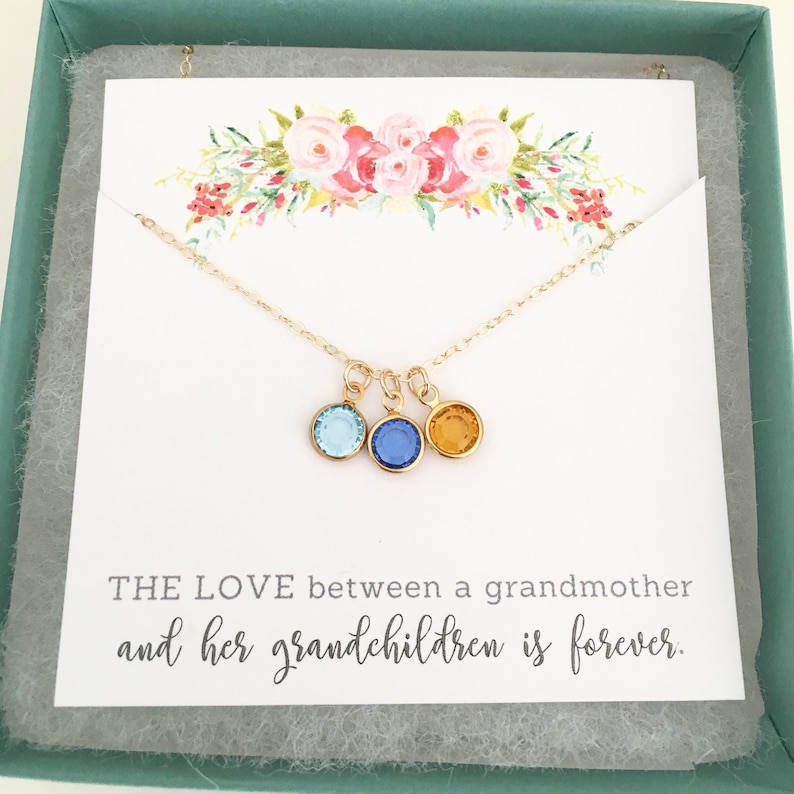 Puede incluir: Collar de oro con tres peque&ntilde;os colgantes, cada uno con un cristal de color diferente: azul claro, azul oscuro y &aacute;mbar. El collar est&aacute; en una caja con una tarjeta que dice: "EL AMOR entre una abuela y sus nietos es para siempre."