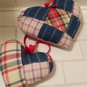 May include: Two patchwork heart-shaped pillows with red, blue, and white plaid fabric. The pillows have red ribbon loops for hanging.