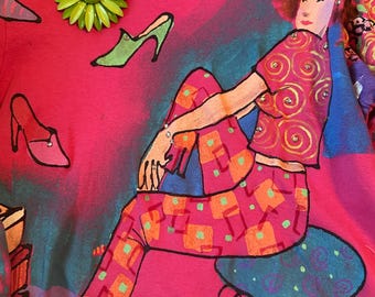 May include: A pink t-shirt with a colorful illustration of a woman in a pink outfit, seated on a blue stool. The shirt features a green flower brooch and shoe graphics. The brand name "KOLORWAY" is visible.
