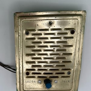 May include: Vintage NuTone intercom station with a brass-colored metal faceplate. The faceplate has a series of horizontal slots for the speaker and a blue knob. The words "LISTEN" and "TALK" are printed on the faceplate.