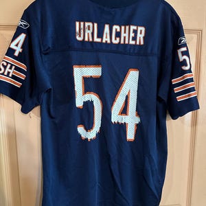 May include: Navy blue mesh jersey with the name "URLACHER" in orange lettering across the upper back and the number "54" in white on the front and back. The sleeves have the number "4" and "5" with orange and white stripes.