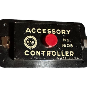 May include: Black accessory controller with a red button and a white label that reads "Accessory Controller No. 1605 Made in USA" and a circular logo with the text "MAR Made in United States of America".