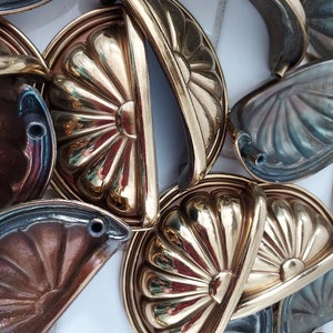 May include: A close-up of several ornate brass cabinet knobs with a decorative, fluted design. The knobs are arranged in a pile, showcasing their intricate details.