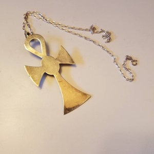 May include: A gold-toned Ankh pendant necklace with a silver chain. The Ankh is a symbol of life in ancient Egyptian culture.