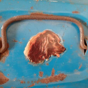May include: A blue metal box with a rusty handle and a sticker of a brown dog's head on the front.