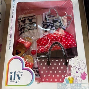 May include: A boxed Minnie Mouse-themed fashion set. The set includes a red polka dot skirt, a matching handbag, sandals, and accessories. The packaging features the text "inspired by minnie mouse, styled for you!" and the Disney "ily 4ever" logo.