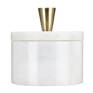 Op de afbeelding: Een cilindervormige witte marmeren houder met een gladde, gepolijste afwerking. De houder is voorzien van een bijpassend rond deksel met een centrale, taps toelopende handgreep van goudkleurig metaal met een geborstelde textuur.