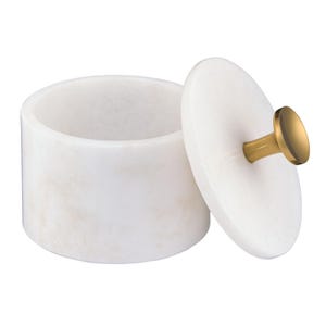 May include: A cylindrical white marble container with a matching circular lid. The lid features a central gold-toned metal knob handle. The container has a smooth, polished surface with subtle natural veining throughout the stone material.