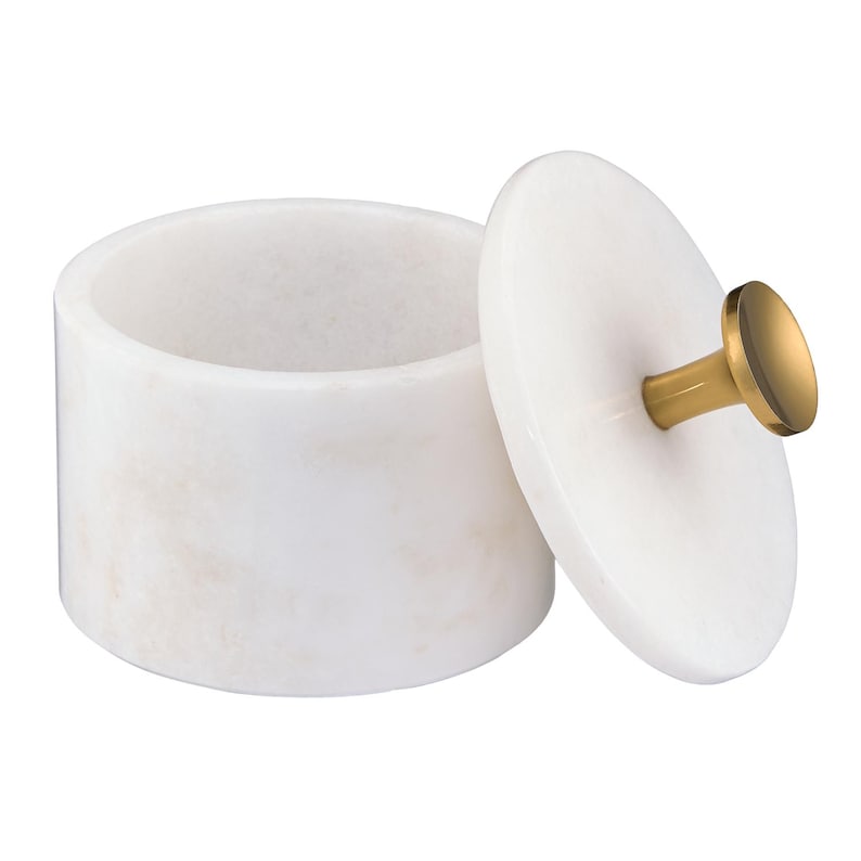 May include: A cylindrical white marble container with a matching circular lid. The lid features a central gold-toned metal knob handle. The container has a smooth, polished surface with subtle natural veining throughout the stone material.