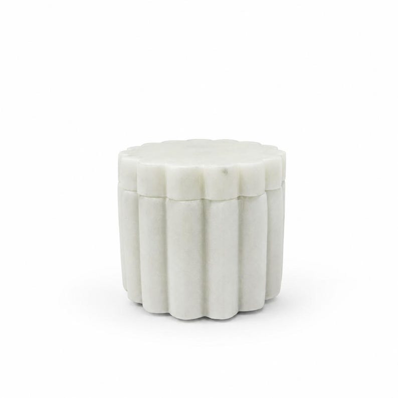 May include: A cylindrical white marble container featuring a scalloped, fluted exterior design. The object consists of a base and a matching removable lid, both crafted from solid stone with a smooth, matte finish and subtle natural veining.