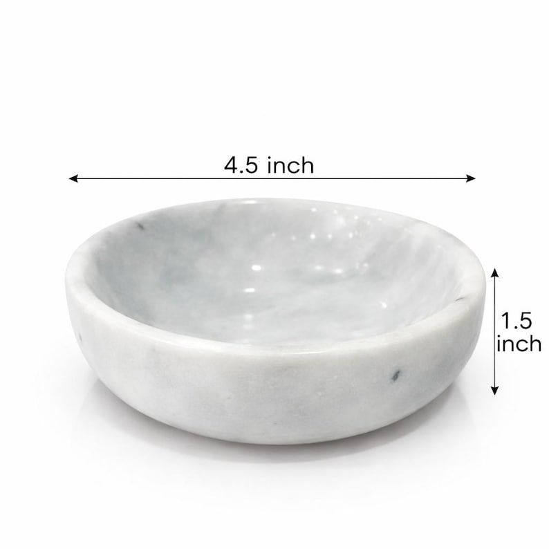Puede incluir: Un cuenco redondo de m&aacute;rmol blanco con vetas grises. El cuenco presenta una superficie interior y exterior lisa y pulida. El texto indica un di&aacute;metro de 11,43 cm y una altura de 3,81 cm, claramente marcados con flechas para la escala.