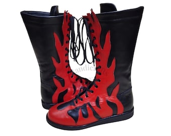 May include: A pair of tall, black leather boots with red flame-like designs. The boots have a lace-up closure and a flat sole. The red flames are outlined in black, creating a striking contrast. The boots are likely for costume or theatrical use.