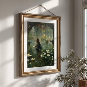 Pu&ograve; includere: Una stampa artistica da parete incorniciata che raffigura una scena boschiva scura e suggestiva con una figura in abito lungo vicino a uno stagno pieno di ninfee bianche, racchiusa in una cornice dorata con passe-partout bianco e corda.