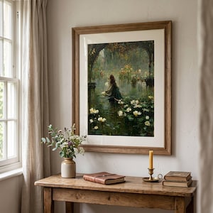 The Lost Lake Witch Painting , oul painting wall art print depicting a figure in a boat on a pond filled with white water lilies, surrounded by dark trees. The artwork is displayed in a wooden frame with a white mat, hanging above a wooden table with a vase of flowers.