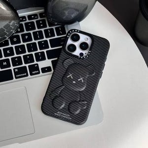 Könnte beinhalten: Schwarze Handyhülle aus Kohlefaser mit einem Bärenmuster. Die Hülle hat eine strukturierte Oberfläche und trägt den Text "BEAR FASHION WORLD OF COMPANION". Die Handyhülle liegt auf einer Laptop-Tastatur.