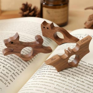 Puede incluir: Tres sujetapáginas de madera con forma de ardilla, murciélago y diseño rectangular. La ardilla y el murciélago tienen nombres grabados. El rectangular tiene el texto "Read another page".