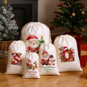 May include: A collection of off-white drawstring bags with Christmas-themed illustrations. Designs include Santa Claus, reindeer, snowmen, Christmas trees, and festive lettering. The bags vary in size and feature red, green, and gold accents.