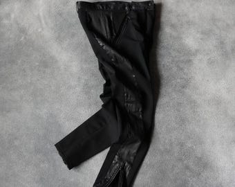 Könnte beinhalten: Schwarze Hose mit lederartigen Einsätzen an den Seiten und Knien. Die Hose hat einen Reißverschluss am Knöchel und einen Knopfverschluss am Bund. Das Material hat ein mattes Finish.