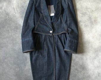 Könnte beinhalten: Ein dunkelblauer Jeansmantel mit einem einzigartigen Design. Der Mantel hat einen Reverskragen, einen Einzelknopfverschluss und ein geschichtetes Oberteil. Die langen Ärmel haben ein Manschettendetail. Ein Etikett hängt am Kragen. Der Mantel hat eine Midi-Länge.