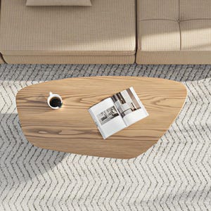 May include: Overhead view of a light wood coffee table with a cup of coffee and an open magazine. The table sits on a patterned rug, near a beige sofa. The coffee table has a unique, organic shape.