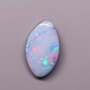 May include: A marquise-shaped opal gemstone featuring a smooth, polished surface with a milky white base color and vibrant flashes of iridescent red, green, and blue light reflecting across its curved, cabochon-cut top and rounded edges.