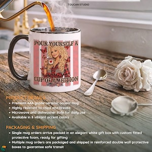 May include: A white ceramic mug with a black handle and interior rim. The mug features a graphic of a blonde woman in a red plaid shirt holding a cup, surrounded by butterflies and the text, Pour Yourself A Cup Of Ambition, with pink stripes.