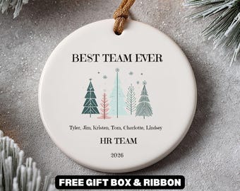May include: A round white ceramic ornament featuring the text BEST TEAM EVER, a graphic of five stylized Christmas trees in green, pink, and blue, and the names Tyler, Jim, Kristen, Tom, Charlotte, Lindsey, HR TEAM, and the year 2026.