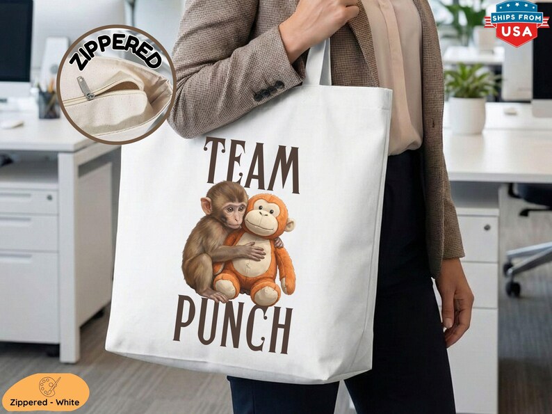 May include: White tote bag with a zippered pocket, featuring the text "TEAM PUNCH" in brown letters. The design includes two hugging monkeys, one brown and one orange. The bag is carried by a person.