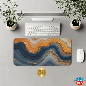 May include: A rectangular mouse pad with an abstract design in shades of blue, orange, and gold. The design resembles agate stone. The words "FREE SHIPPING" are printed on a gold sticker. A white keyboard and mouse are also visible.