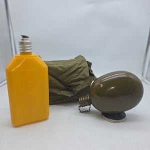 May include: An olive green canteen with a metal cap and a chain, a yellow plastic bottle, and a green canvas bag. The canteen has a silver base. The yellow bottle has a silver cap. The bag is folded.