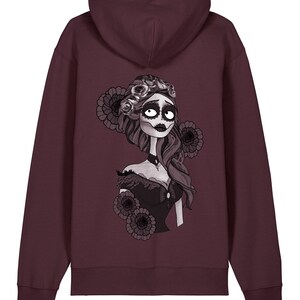 Può includere: Felpa con cappuccio bordeaux con un'illustrazione in bianco e nero di una donna con accenti floreali, che ricorda il Giorno dei Morti. L'opera d'arte è sul retro della felpa con cappuccio, mostrando un'estetica gotica.