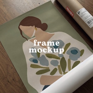 Puede incluir: Un póster enrollado y una impresión con una mujer con un ramo de flores. La impresión tiene las palabras "frame mockup" en blanco. El póster está en un tubo marrón con una pegatina "frágil".