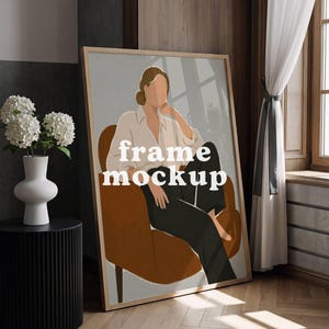 May include: A large framed art print mockup leaning against a wall. The artwork features a minimalist illustration of a person in a chair. The words "frame mockup" are printed on the artwork. A white vase with flowers and a black side table are in the foreground.