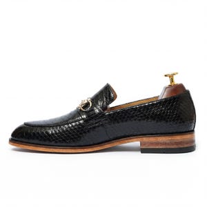 Side profile of mens dress loafers on wooden shelf Leathersmerchant