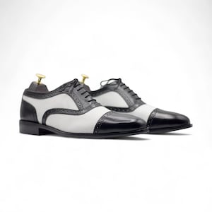 Side profile showing the classic cap toe design and sleek black and white leather finish, suitable for weddings and events.