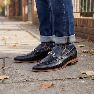 Mens black snake print loafers with gold horsebit detail on foot