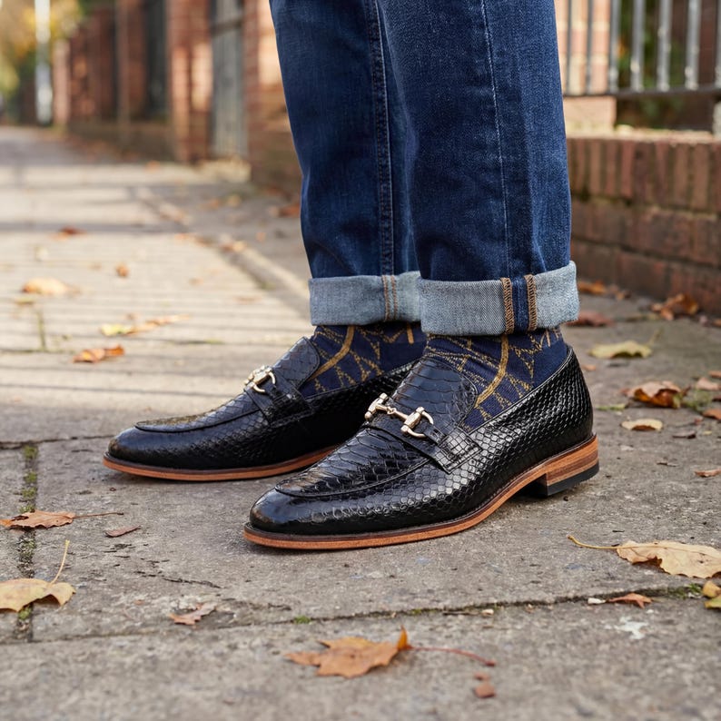 Mens black snake print loafers with gold horsebit detail on foot