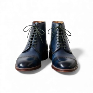 Close up of a single handmade leather dress boot with perforations.