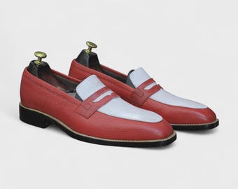 Pode incluir: Um par de mocassins de couro vermelho com detalhes brancos na gáspea e na tira. Os sapatos têm um acabamento texturizado, solas pretas e são exibidos em formas. Design clássico, com cerca de 25 cm de comprimento.