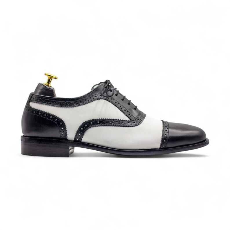 Side profile showing the classic cap toe design and sleek black and white leather finish, suitable for weddings and events.