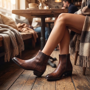 Woman wearing textured brown python leather boots in a cozy rustic cafe setting