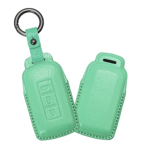 May include: A pair of mint green leather key fob covers. One cover is attached to a metal ring with a matching leather strap. The other cover is separate. Both covers have a textured surface and stitched edges.