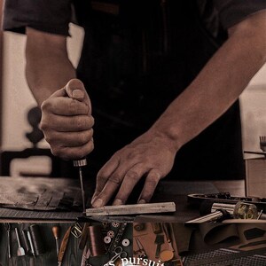 Puede incluir: Un artesano trabajando con cuero, utilizando una herramienta manual para dar forma a un trozo de material. La imagen muestra varias herramientas y suministros de marroquiner&iacute;a, incluyendo cuchillos, agujas e hilo. El texto en la imagen dice "relentless pursuit of perfect".