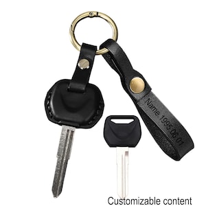 May include: Black leather keychain with a gold-colored ring and a key. The keychain has a strap with the engraved text "Name.1995.06.01". The image also shows a spare key and the words "Customizable content".