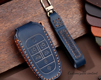 May include: A blue leather car key fob cover and matching keychain with gold-colored hardware. The key fob cover has embossed buttons and a stitched border. The keychain is engraved with "David 1995.06.01".