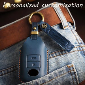 May include: A blue leather car key fob cover with orange stitching, featuring a brass-toned metal ring and a matching blue leather strap embossed with the number 66666666. The text Personalized customization is visible at the top of the image.