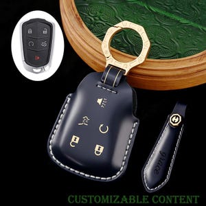 Puede incluir: Una funda para llavero de cuero azul marino con un anillo y detalles dorados. La funda tiene costuras blancas e iconos dorados. También se incluye una etiqueta azul marino a juego con la palabra "grace". El texto "CUSTOMIZABLE CONTENT" está en la parte inferior.