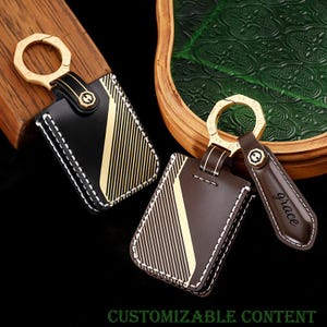 May include: Black and brown leather keychains with gold accents and white stitching. Each keychain features a rectangular holder with a diagonal gold stripe design. One keychain has a small tag with the word "grace". The text "CUSTOMIZABLE CONTENT" is at the bottom.
